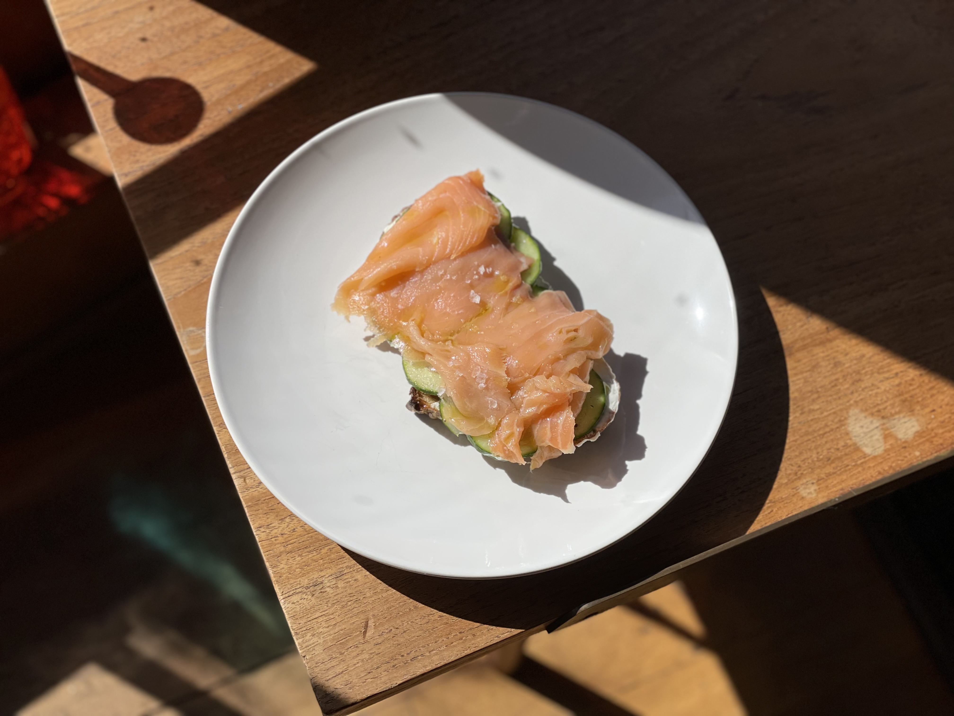 Smoked salmon on toast with cucumber slices and sea salt on a white plate