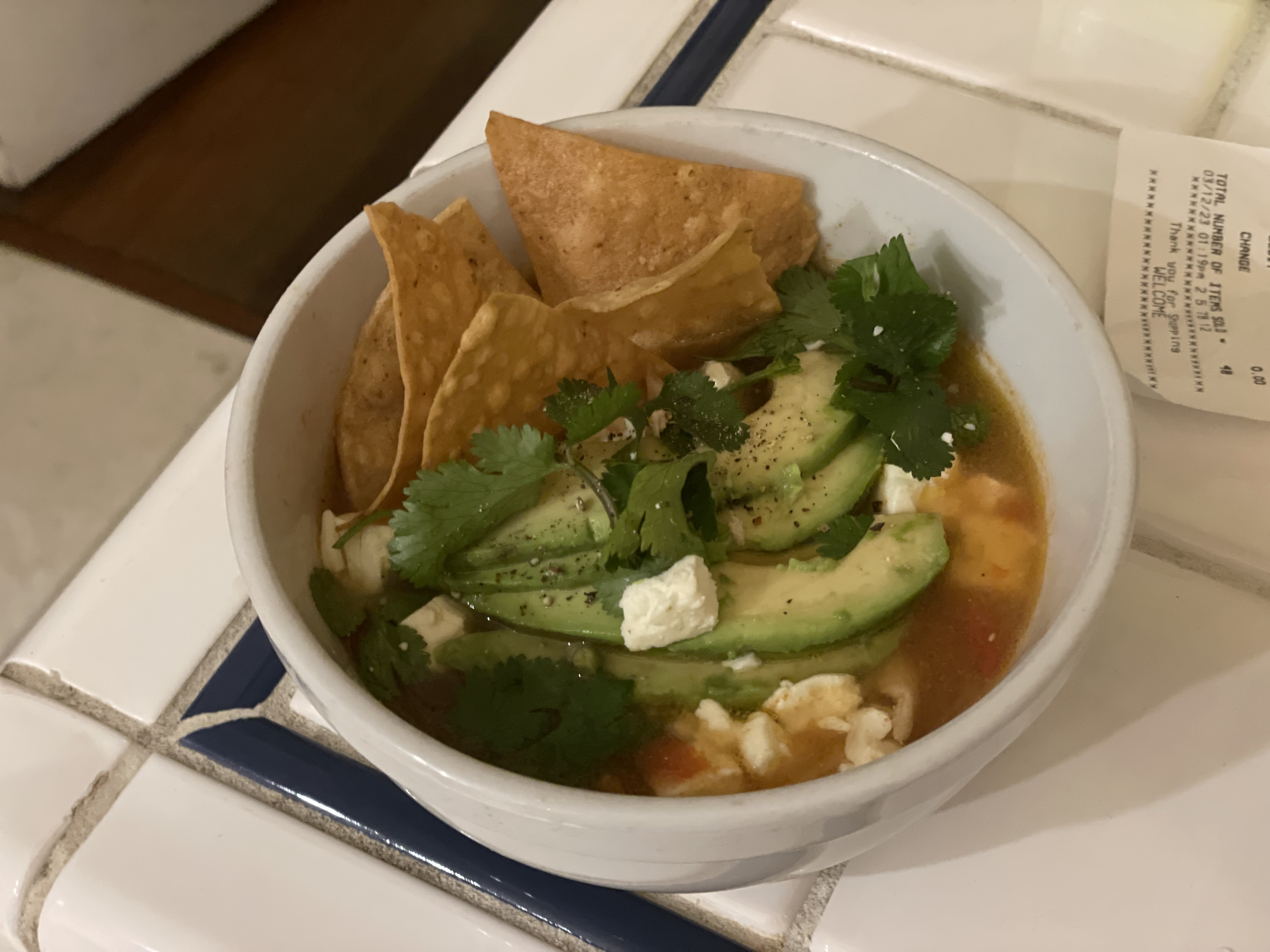 Chicken tortilla soup with avocado, cotija cheese, cilantro, and tortilla chips