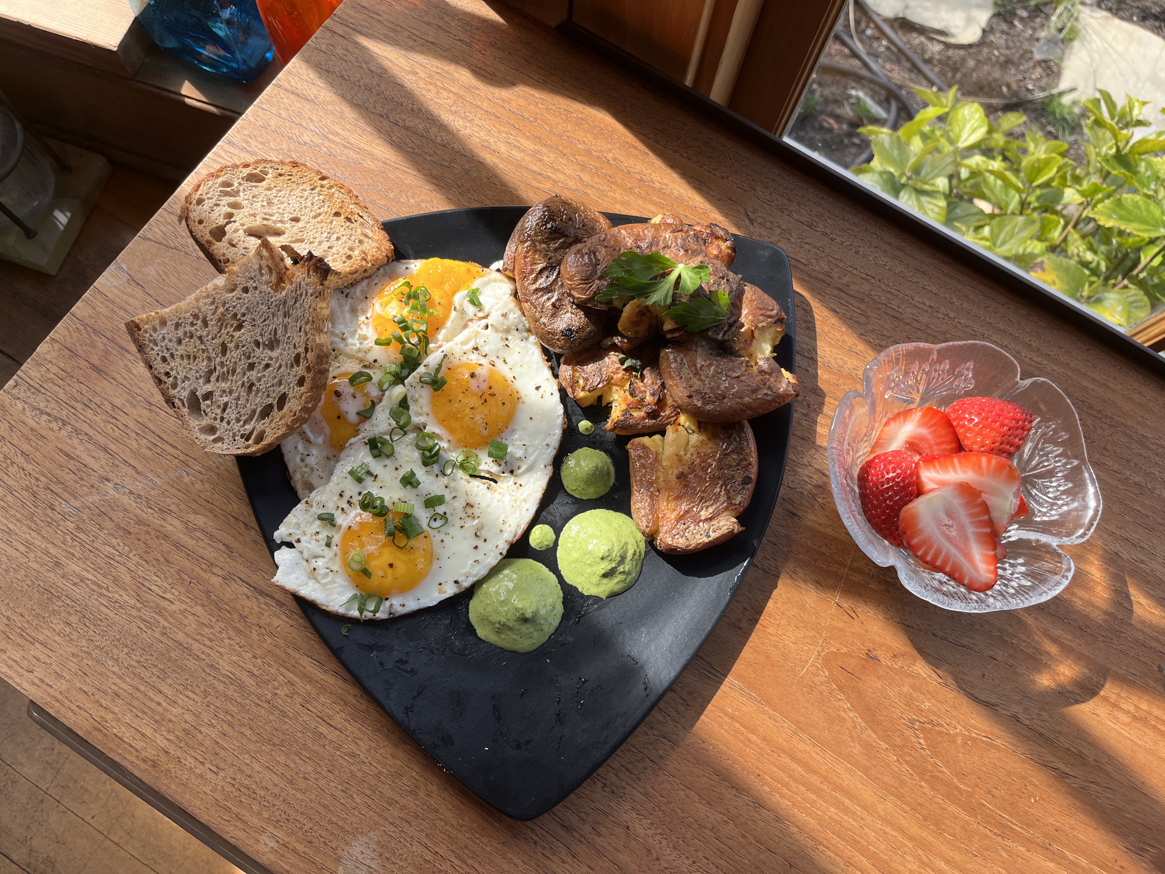 Fried eggs with sautéed mushrooms, toasted sourdough, and fresh strawberries