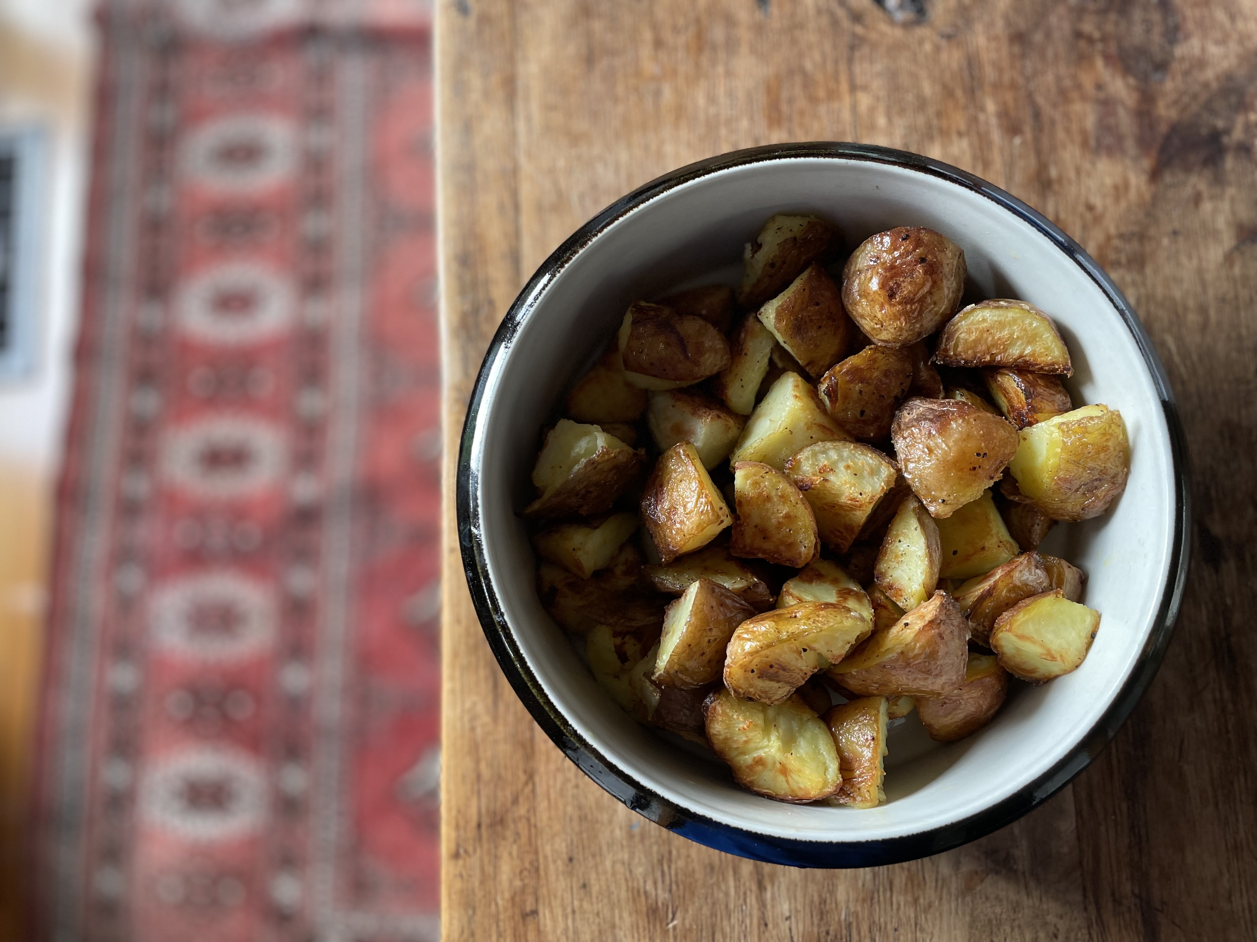 Roasted potatoes in a white bowl with black rim