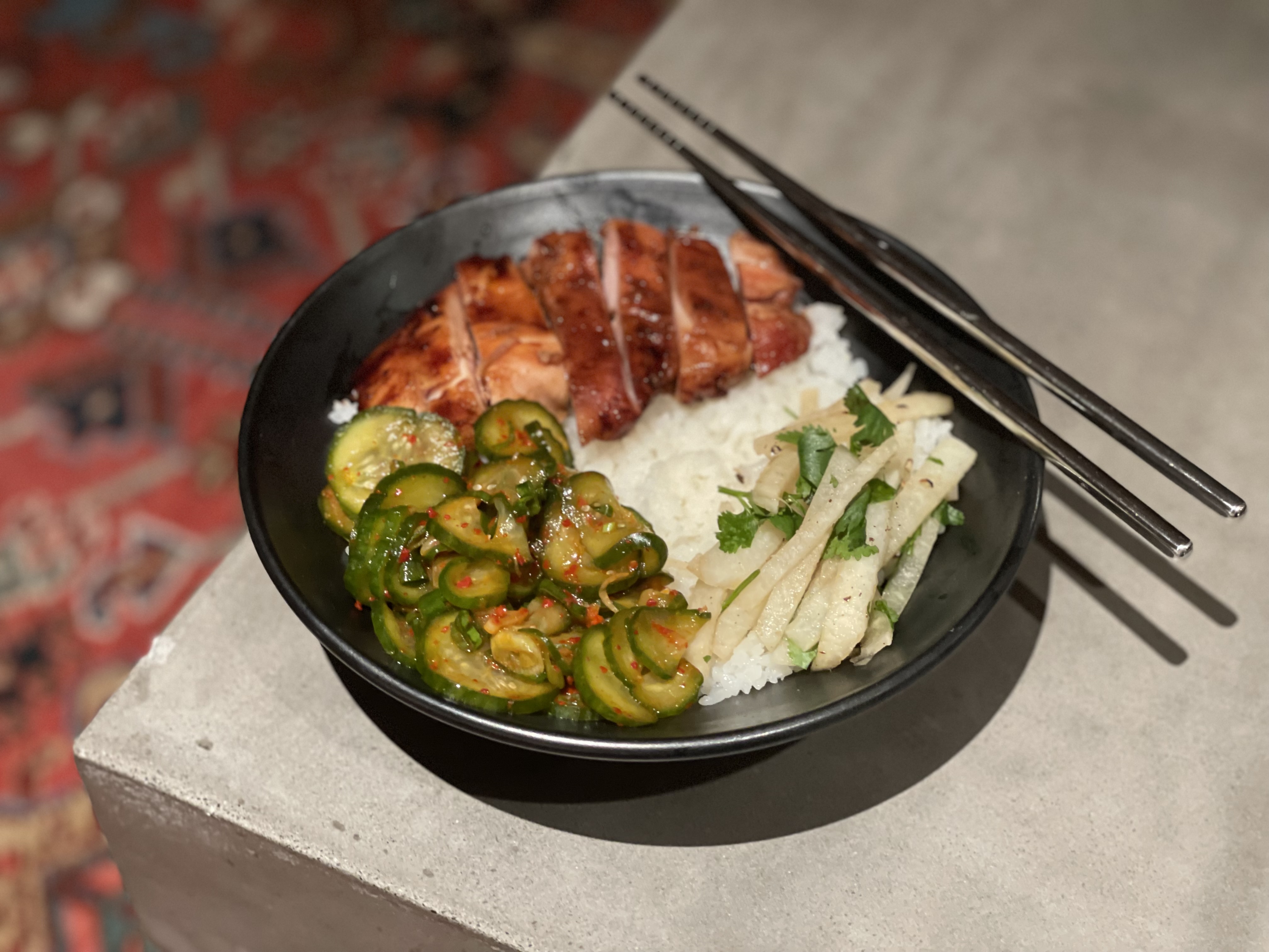 Bowl of rice topped with sliced meat, vegetables, and cilantro