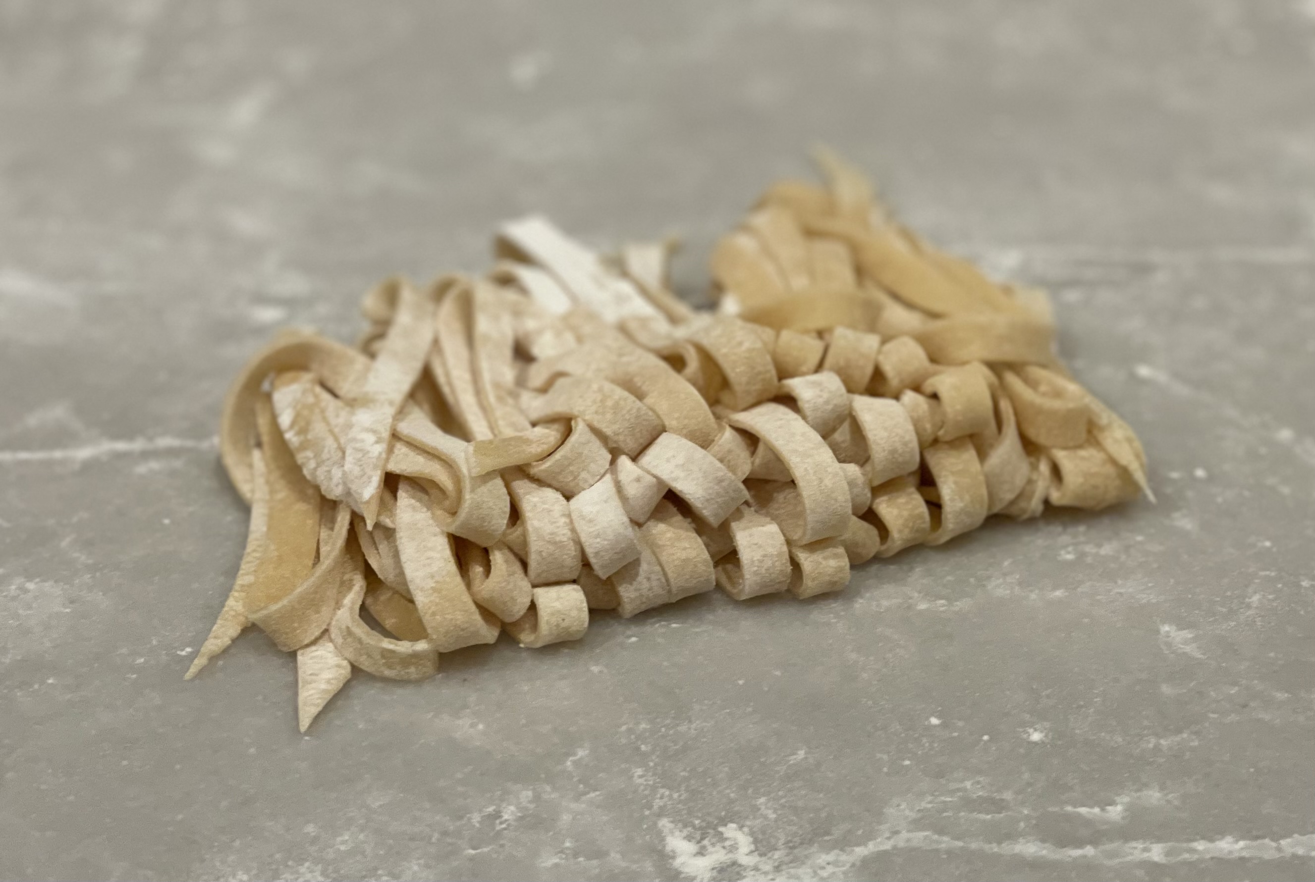 Handmade fresh pasta ribbons dusted with flour on a surface