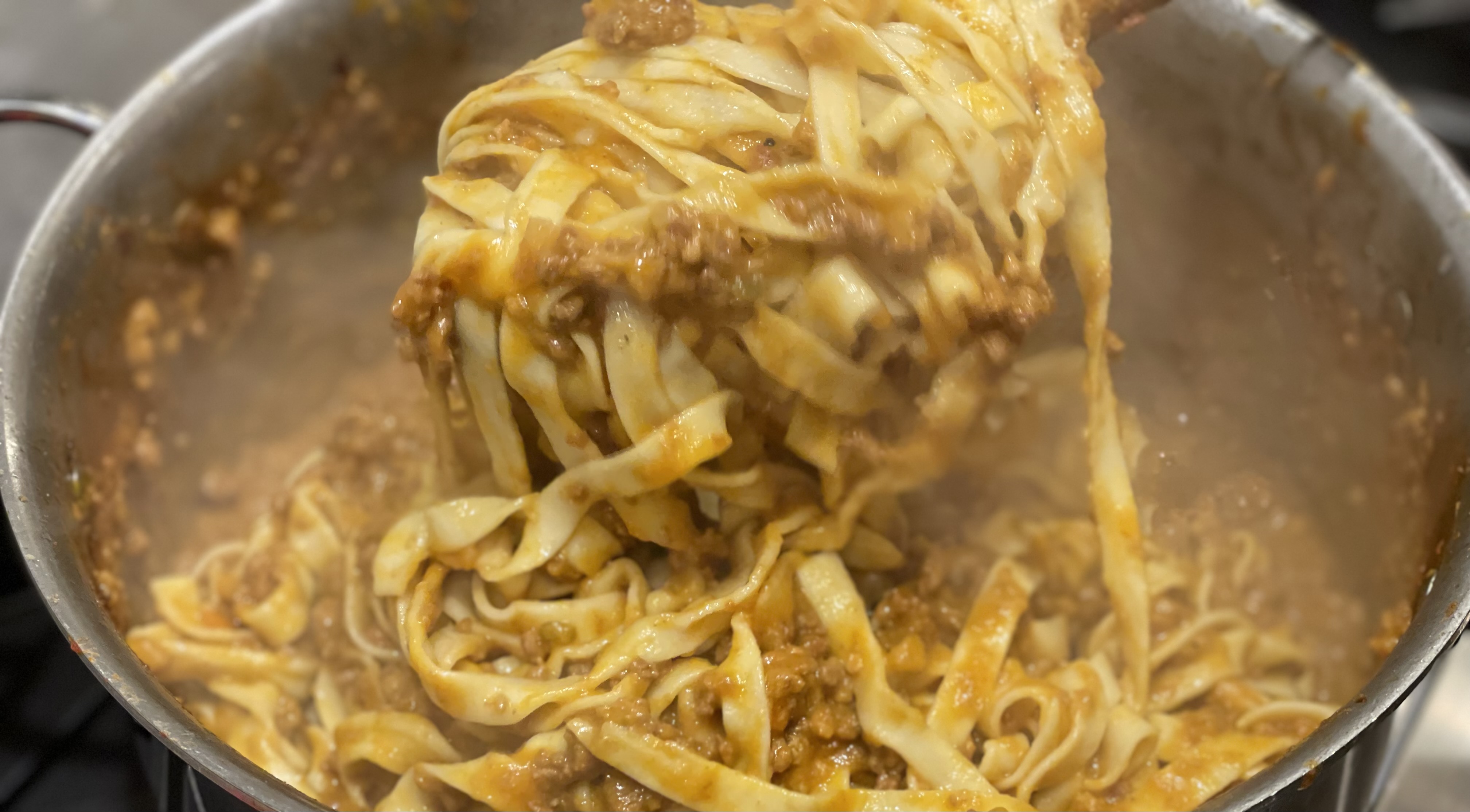 Pasta being lifted from a pot with a fork, cooking in progress