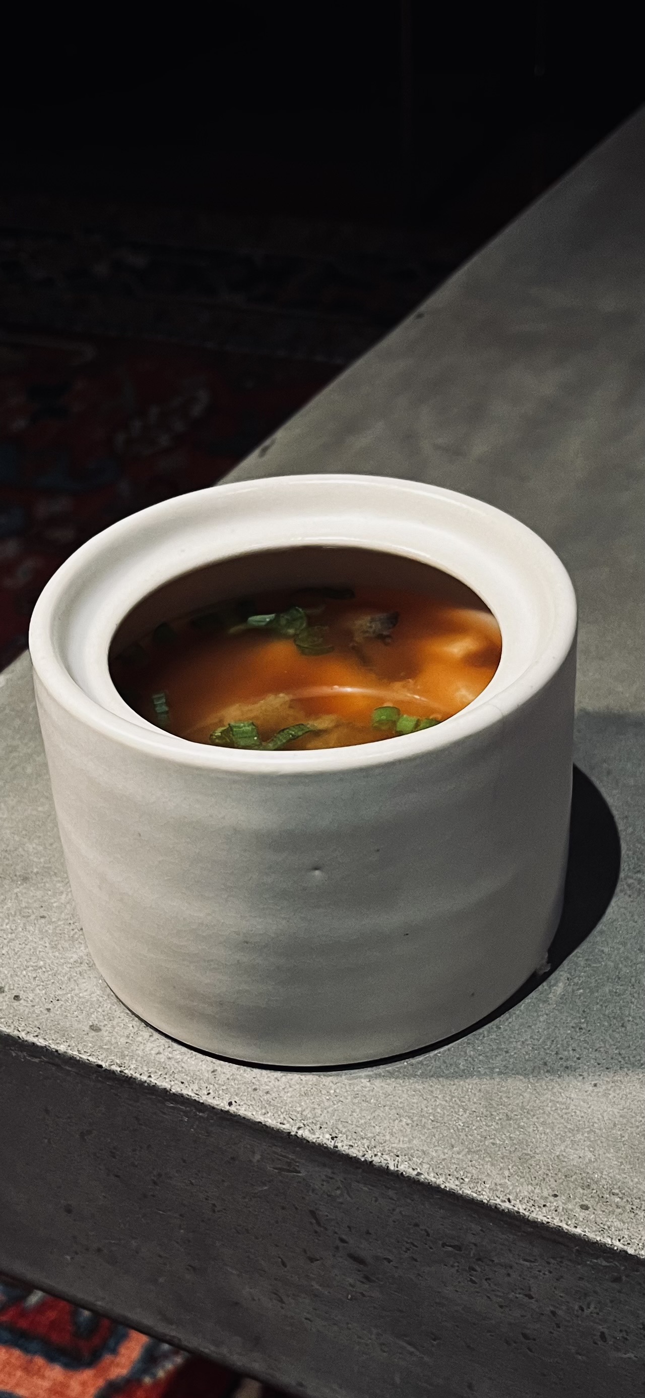 Creamy soup in a white ceramic vessel with herb garnish