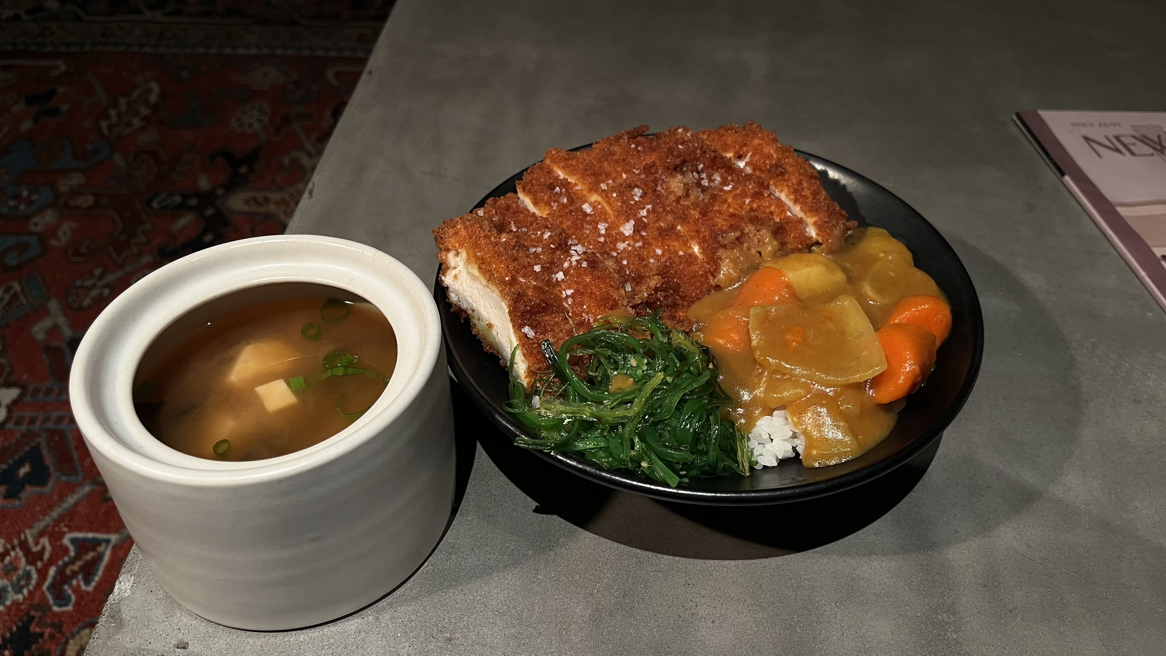 Katsu curry bowl with breaded cutlet, Japanese curry, seaweed salad, and miso soup