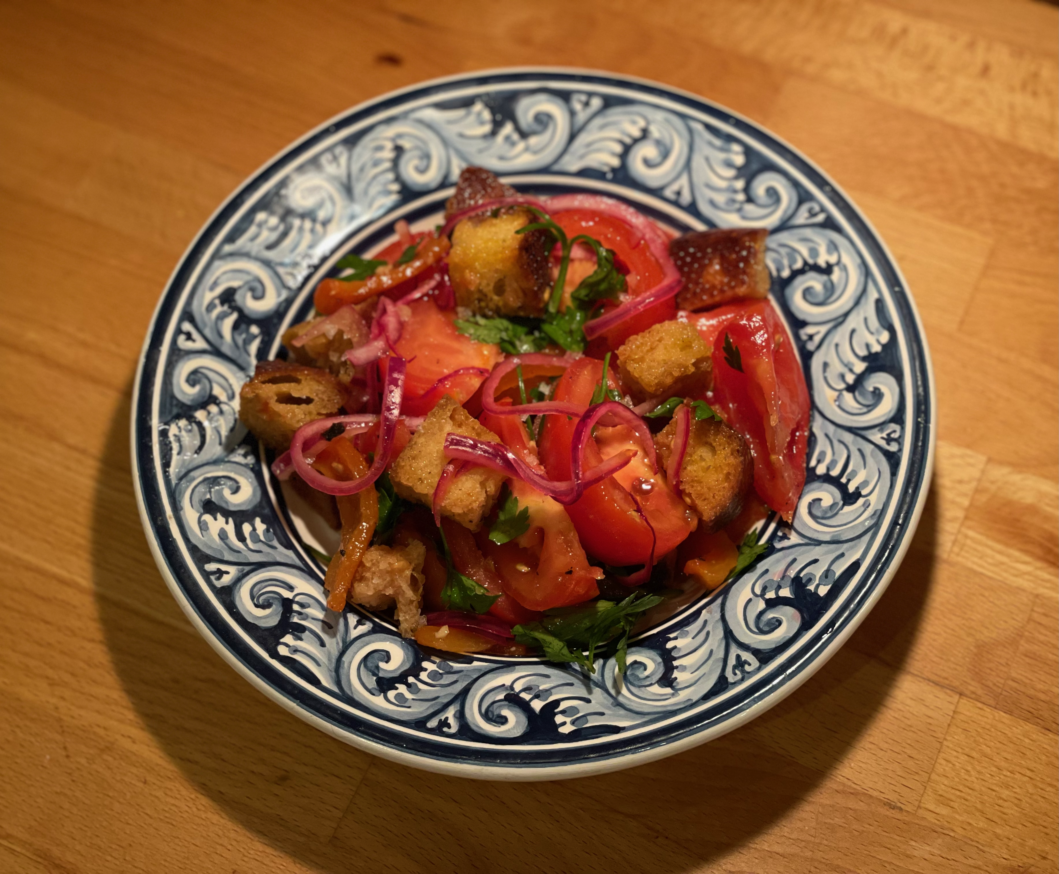 Panzanella salad with tomatoes, croutons, pickled red onion, and herbs on a decorative plate