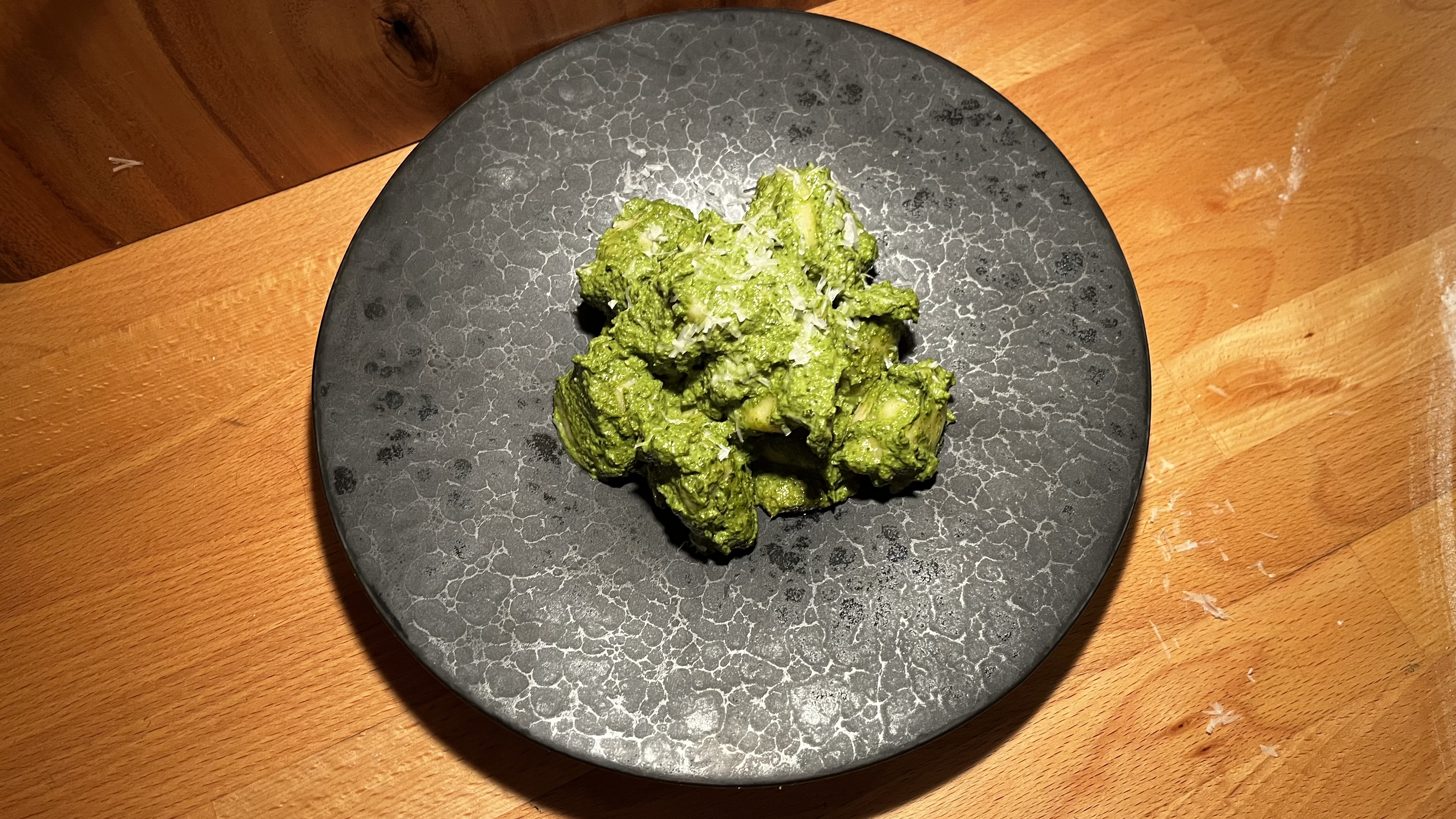 Broccolini with bright green herb sauce on a dark textured plate